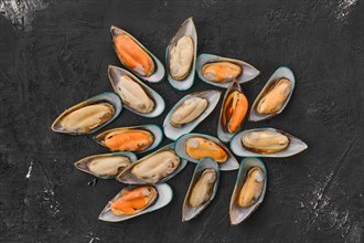 Raw large mussels in half shell on black background