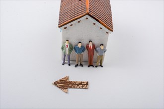 Tiny figurine of men and an arrow in front of a model house