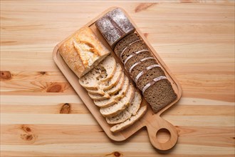 Top view of white and brown bread on wooden cutting board