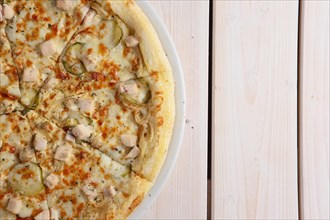 Fresh baked pizza with chicken fillet and pickled cucumber