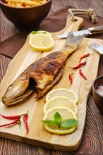 Fried sea bass with fried potato on wooden cutting board