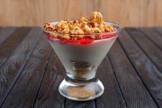 A cup of yoghurt with cherry syrup decorated with caramel popcorn