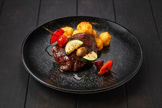 Grilled beef with vegetables and potato balls on a plate