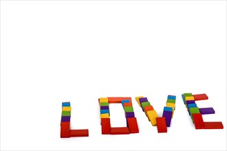 Colorful wooden dominos write the word love on a white background