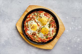 Top view of eggs with bell pepper and tomato baked in oven in cast-iron skillet