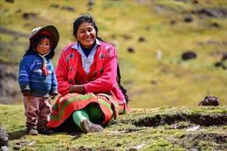 Quechua Indian family in traditional dress sitting in a meadow