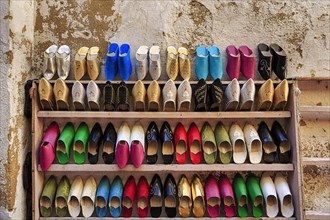 Many colourful Moroccan slippers lined up on a shelf
