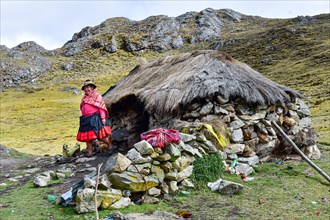 Quechua Indian woman in traditional dress in front of her hut