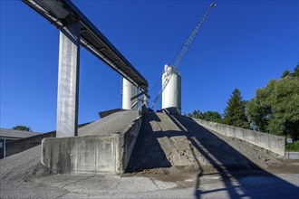 Steel silos and shovel crane with gravel piles and conveyor belt