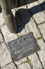 Foot of the pilgrim statue in front of the Protestant St. Jakob's Church with inset floor plate to the Way of St. James to Santiago de Compostella