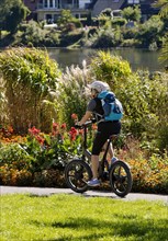 Bicycle rider on the Ruhr valley cycle path with lush vegetation at the reservoir