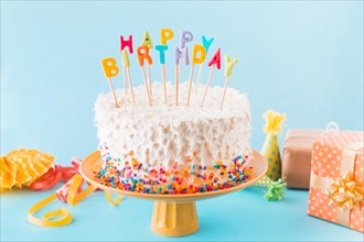 Birthday cake with gift accessories blue background