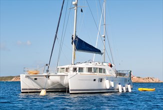 Catamaran with small dinghy moored to mooring buoy