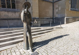 Pilgrim statue in front of the Protestant St. Jakob's Church with inset floor plate to the Way of St. James to Santiago de Compostella