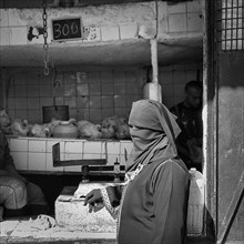 Traditionally dressed Muslim woman with niqab stands at poultry stall