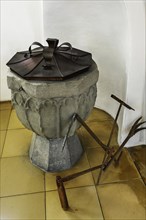 Baptismal font with antique agricultural implement