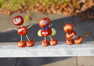Three chestnut figures with grapes in the evening light