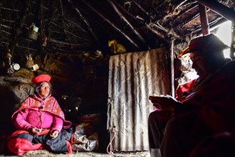 Quechua Indians in traditional dress sitting in their hut