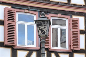 Half-timbered house with window shutter and lantern with historical motif