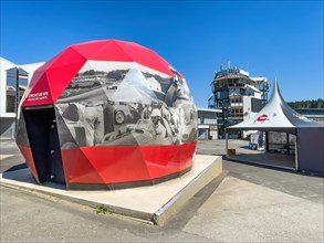Open Air Museum Exhibition space with exhibition on racing history in the form of walk-in giant helmet with left entrance outside historical photos of car races