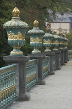 A row of golden lidded vases on a balustrade in the castle garden