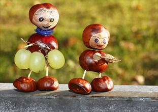 Two chestnut figures with grapes in the evening light