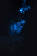 Blue smoke against black background