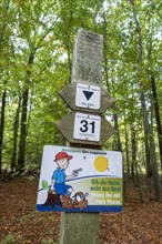 Sign with the inscription Don't give nature the rest! Take it home with you. under hiking signs in the autumnal forest