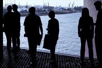 People silhouetted in the Elbe Philharmonic Hall with a view of Hamburg harbour