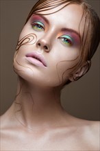 Beautiful girl with bright colored makeup and wet strands of hair on the face. Creative image. Picture taken in the studio