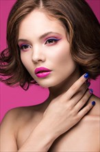 Beautiful model girl with bright makeup and colored nail polish. Beauty face. Short colorful nails. Picture taken in the studio on a pink background