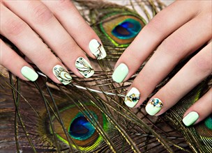 Art design manicure with peacock feather on female hands. Close-up. Fashion nails. Photos shot in studio