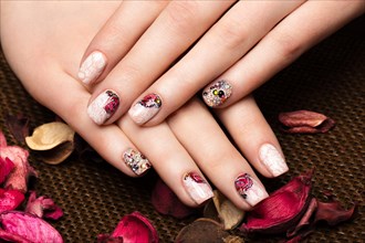 Beautiful manicure with flowers on female fingers. Nails design. Close-up. Picture taken in the studio on a white background