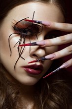 Portrait of woman in the image of spider with creative art makeup and long nails. Manicure design
