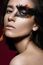 Beautiful girl in the image of the Phoenix bird with creative makeup .The beauty of the face. Photos shot in studio