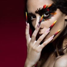 Beautiful girl in the image of the Phoenix bird with creative makeup and long nails. Manicure design. The beauty of the face. Photos shot in studio