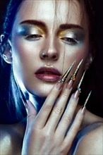 Beautiful girl with creative golden and silver glitter make-up and long nails art. The beauty of the face. Photos shot in studio