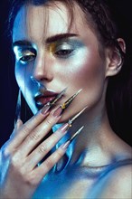 Beautiful girl with creative golden and silver glitter make-up and long nails art. The beauty of the face. Photos shot in studio
