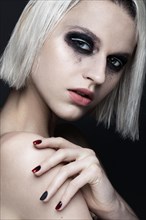 Beautiful blond girl with dark smokey makeup and art manicure design nails. beauty face. Photos shot in studio