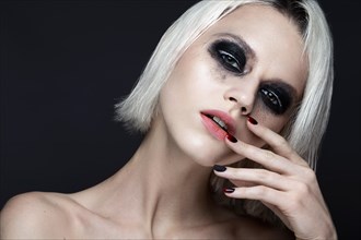 Beautiful blond girl with dark smokey makeup and art manicure design nails. beauty face. Photos shot in studio