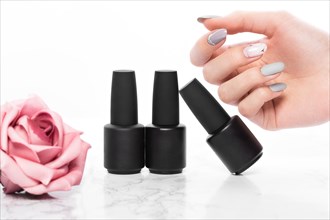 Black bottles of nail polish on a background of flowers. Manicure design