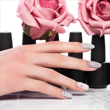Black bottles of nail polish on a background of flowers. Manicure design