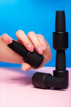 Black bottles of nail polish on a colorful background. Manicure design