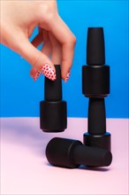 Black bottles of nail polish on a colorful background. Manicure design