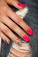 Bright neon manicure on female hands on the background of jeans. Nail design. Beauty hands