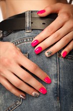 Bright neon manicure on female hands on the background of jeans. Nail design. Beauty hands