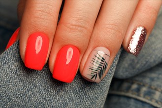 Bright neon red manicure on female hands on the background of jeans. Nail design. Beauty hands