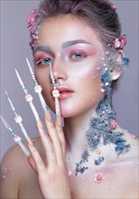 Beautiful girl in the image of a sweet fairy with art make-up and with long design nails. Creative manicure. Photo taken in the studio