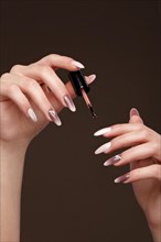 Beautiful classic manicure on female hand with oil for cuticles. Close-up. Picture taken in the studio