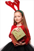 Beautiful little girl in a New Year's image with boxes of gifts in hands and deer horns on her head. Photo taken in the studio